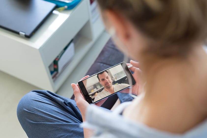 A woman video chatting at home with a loved one in recovery.