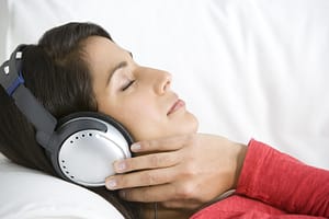 A woman wearing headphones achieves relaxation and other sound therapy benefits.
