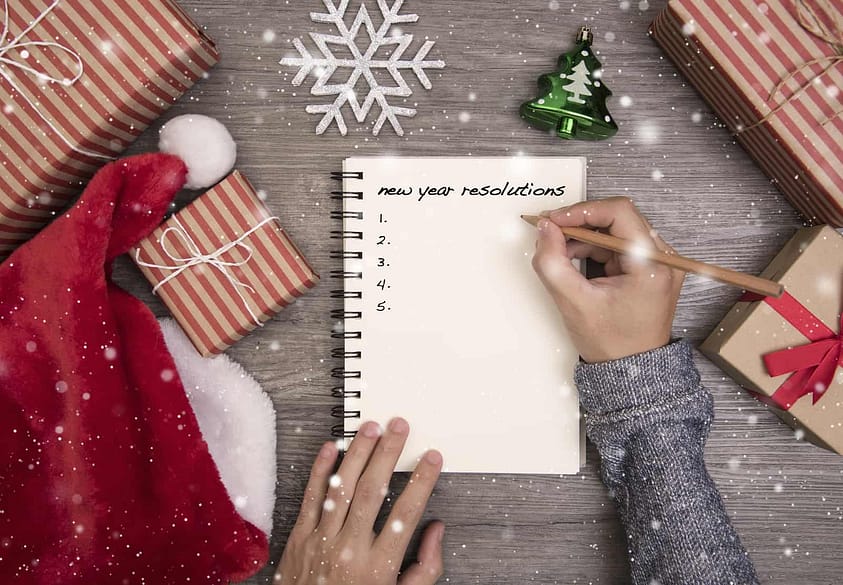 A woman writes down her list of New Year’s resolutions during the holidays.