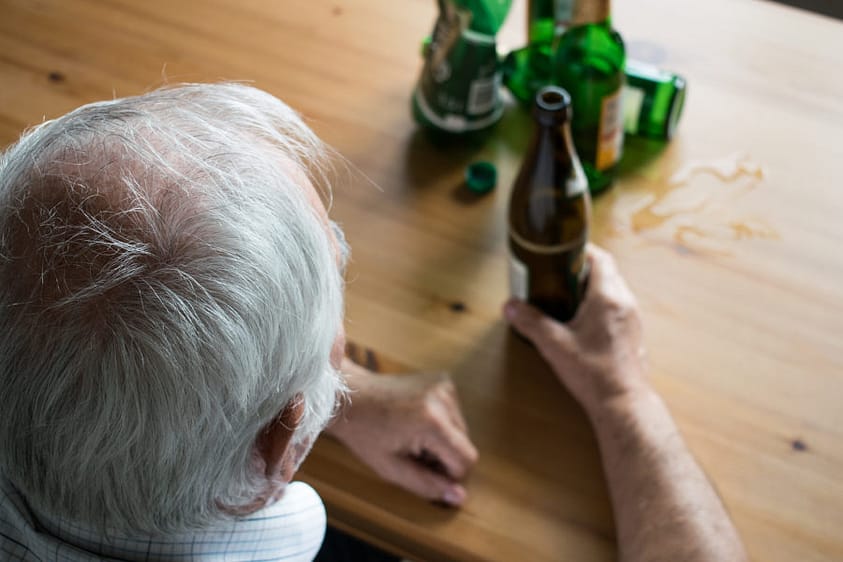 A senior man drinking alcohol at home