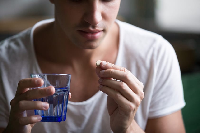 Young man taking a painkiller to relieve pain.