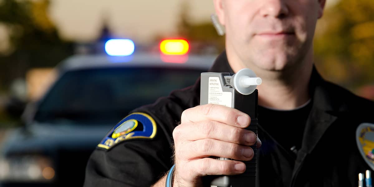 a police officer holding a breathalyzer to test for dui vs dwi
