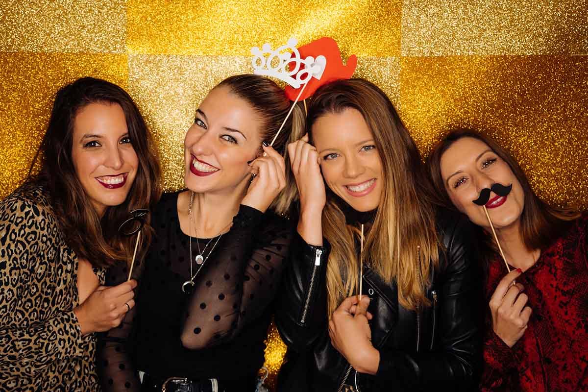 four women posing in a photo booth spending a sober New Years together