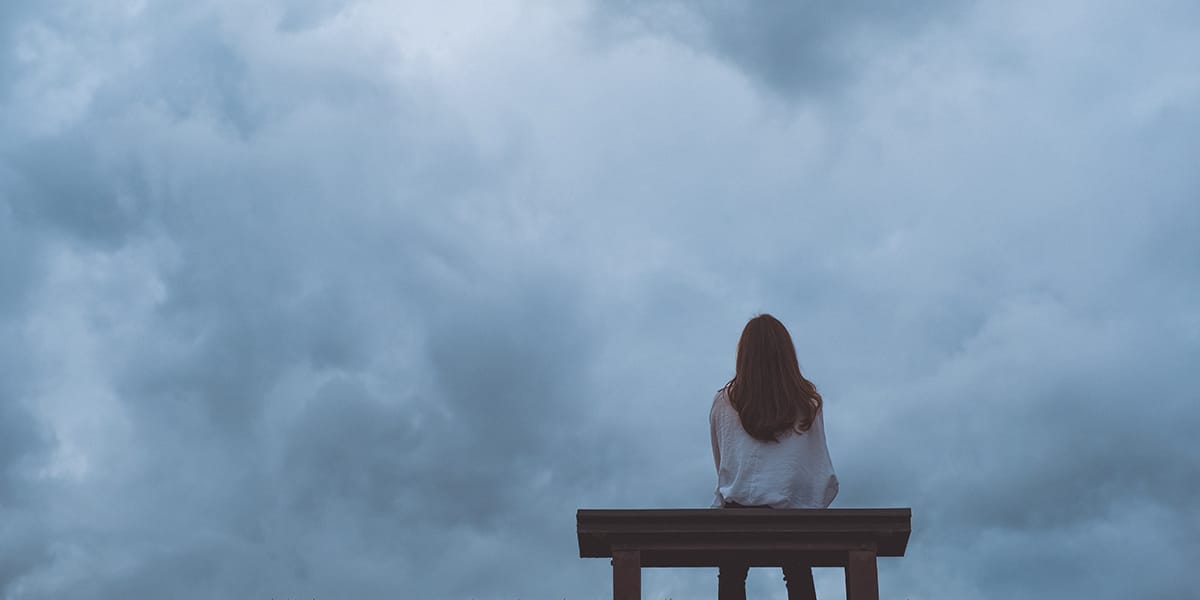 a woman looking at a storm while experiencing signs of stress