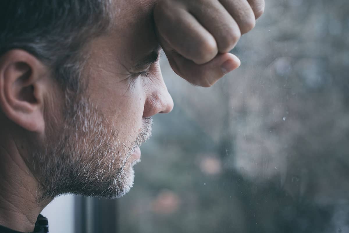 a man looking out the window thinking about dependency vs addiction