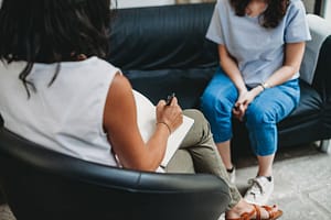 Woman sits on couch and discusses with therapist coping skills for depression