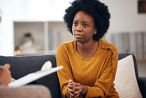 Woman sits and listens to therapist in her anger management program