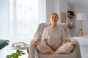 Woman sits in yoga pose on chair as she enjoys a holistic approach to mental health