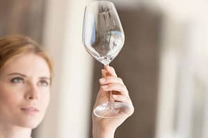 Woman looks at empty wine glass and wonders if alcohol can cause anxiety