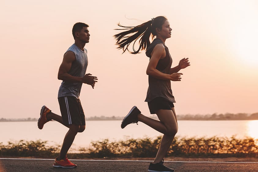 young couple runner running on running road in city park