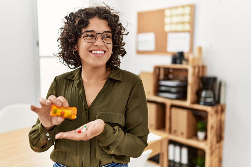 Young woman takes a Vivitrol pill out of bottle