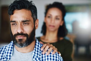 a woman touches her husband's shoulder after learning how addiction and codependency connect
