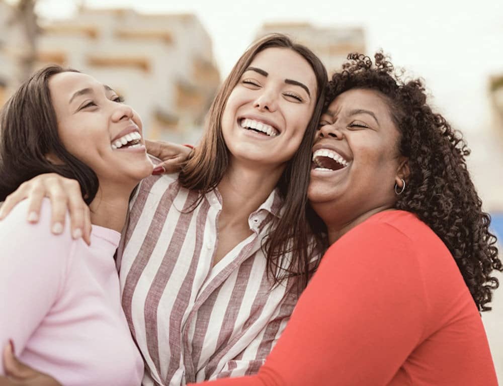 group of three women hugging and laughing