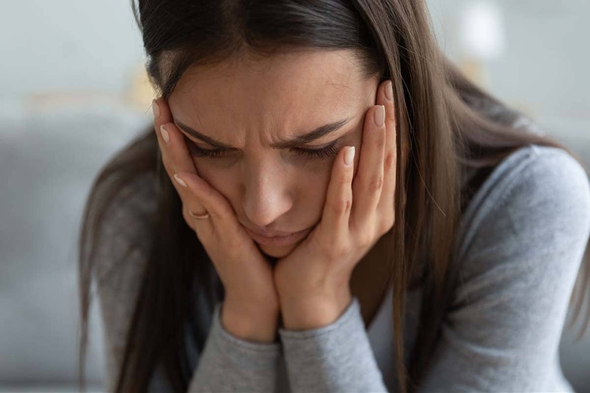 a woman clasps her face in her hands as she thinks about opioid withdrawal