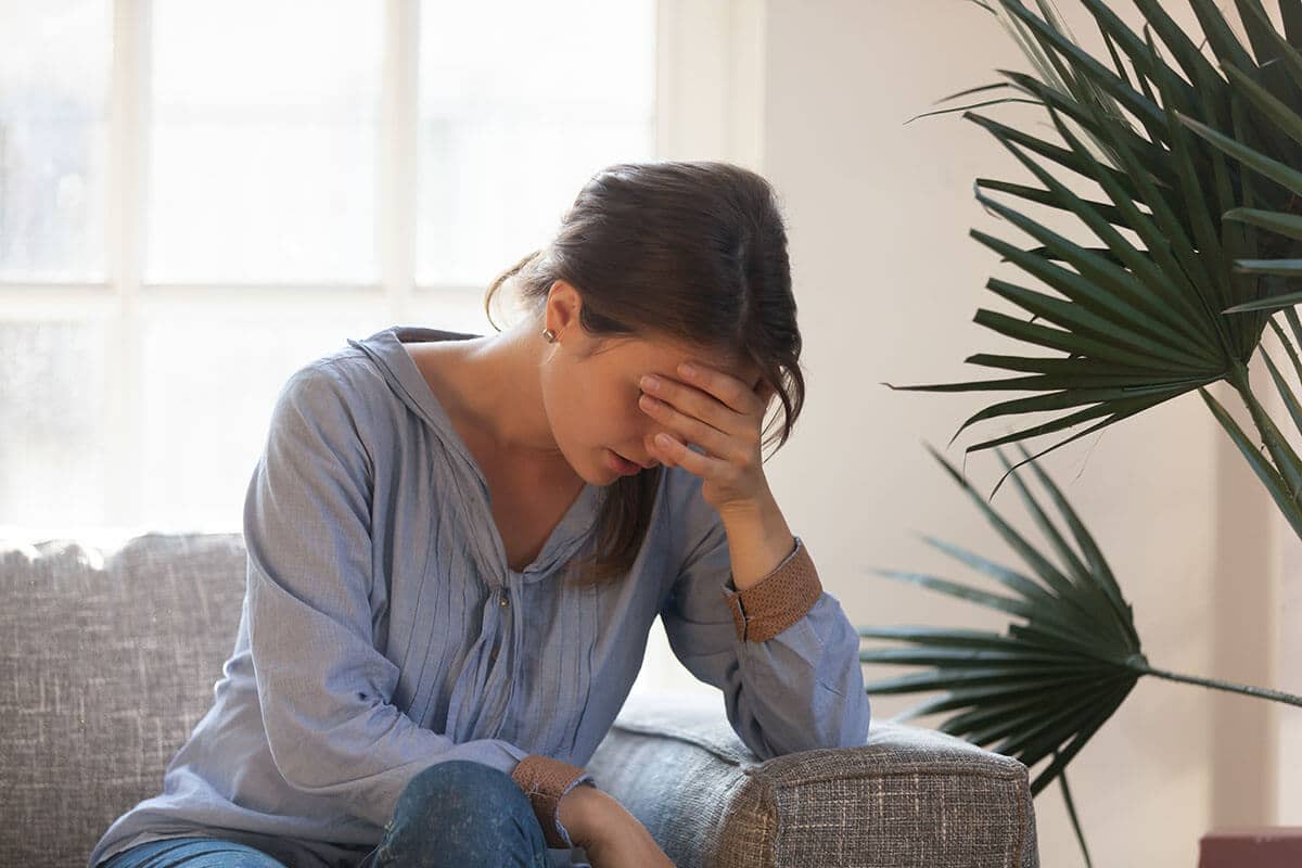a woman holds her head in her hand as she considers the relapse definition