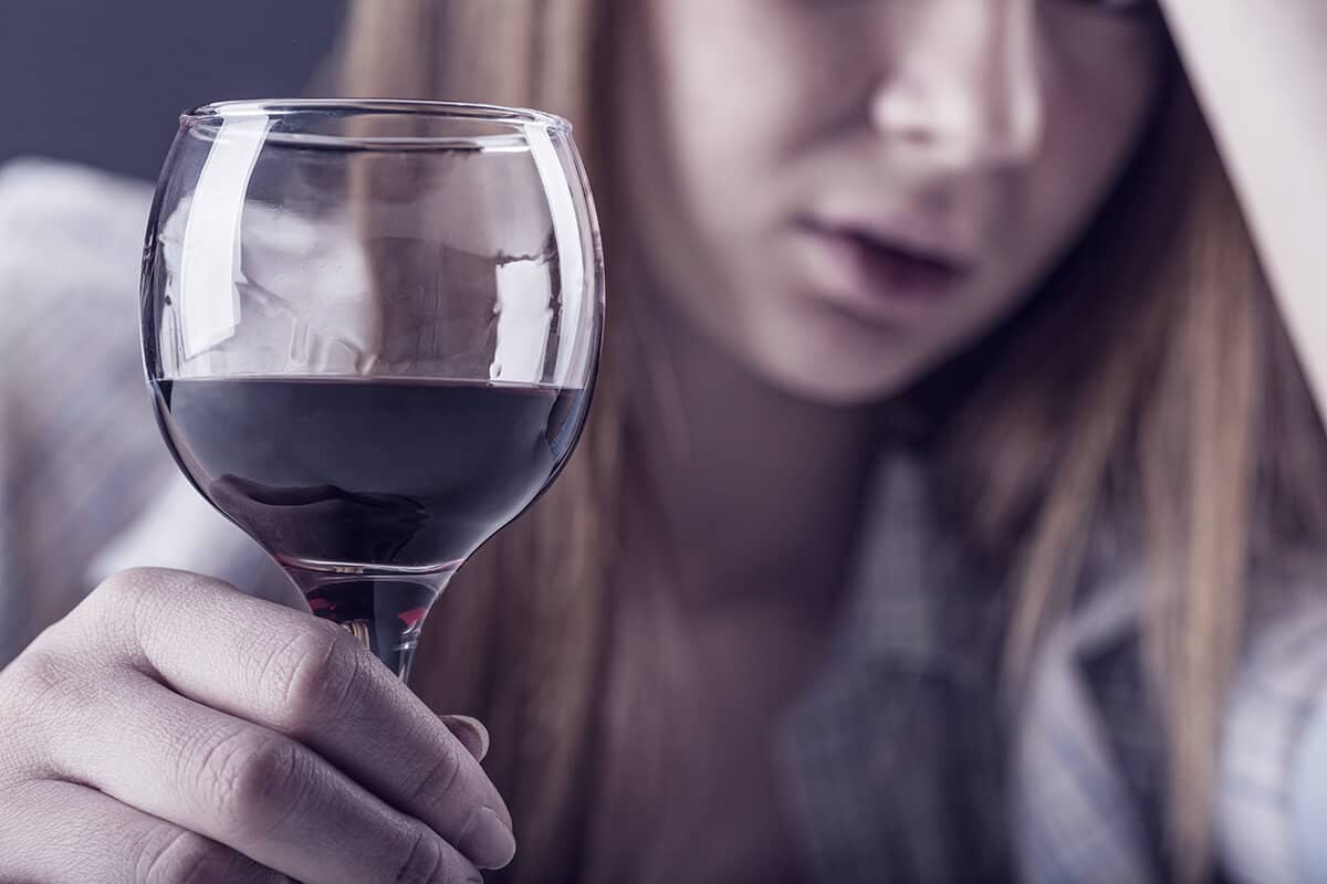 woman drinking wine and asking what is drunkorexia