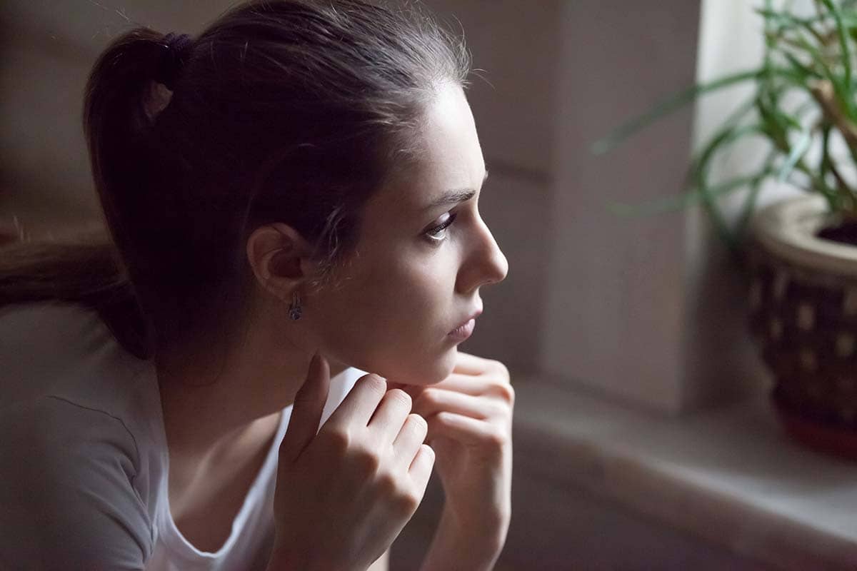 young woman sitting at home thinking about relapse prevention techniques