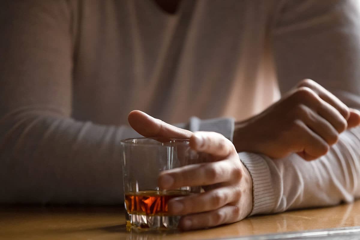 a male holding a glass of alcohol thinking about how to stop alcohol addiction