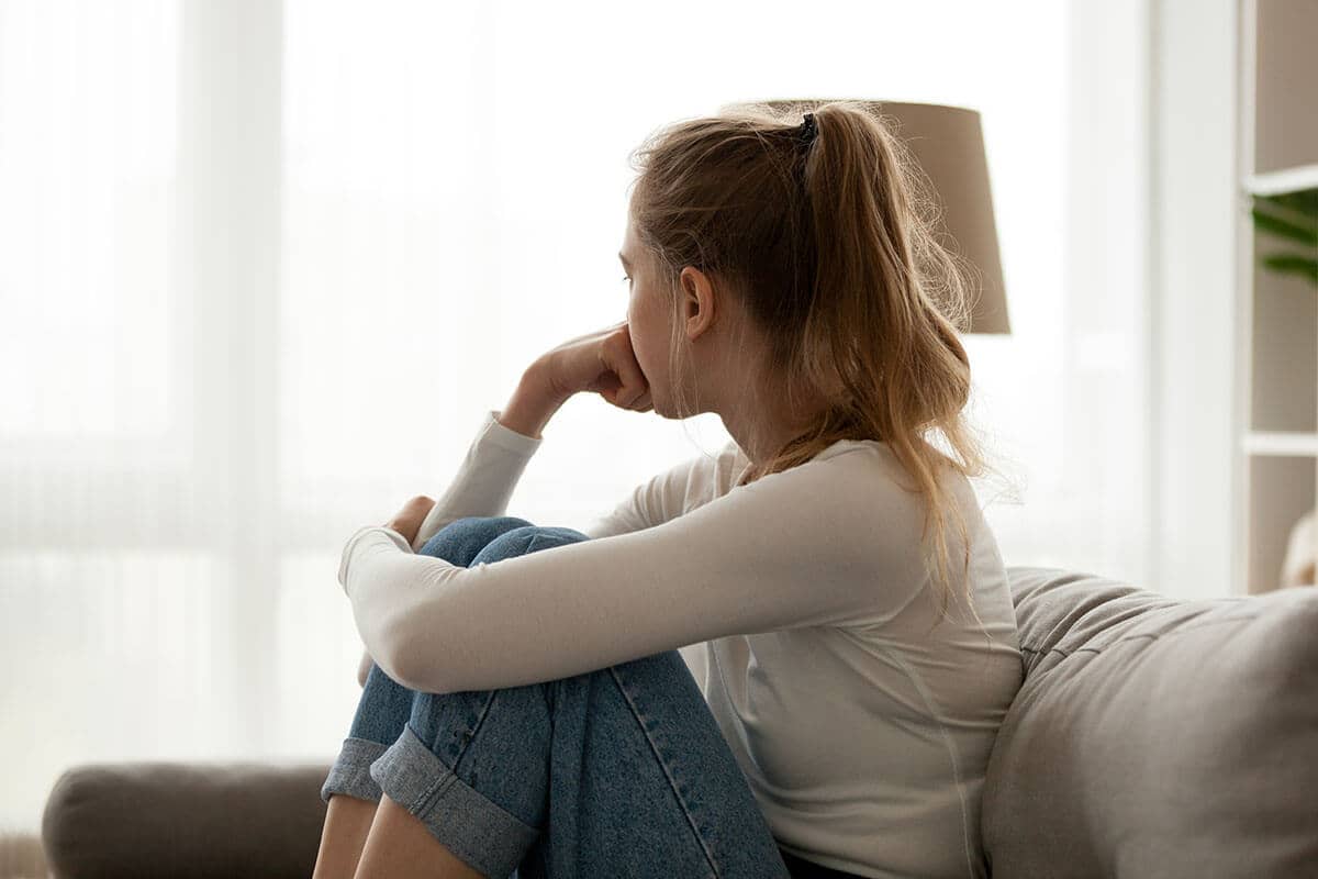 worried young woman sitting down wonders what causes drug addiction
