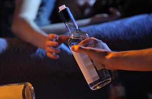 woman handing off bottle displays alcoholic behavior