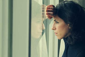 woman looking out the window wonders about opioid vs opiate