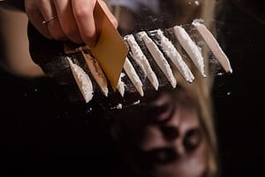 person doing lines on mirror suffers from cocaine effects