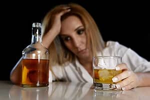 A woman drinking at a bar wonders if she has a need for alcohol treatment centers for women