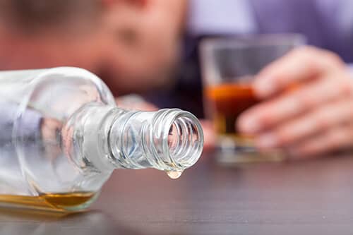 Man passed out with drink in his hand displays alcoholic symptoms