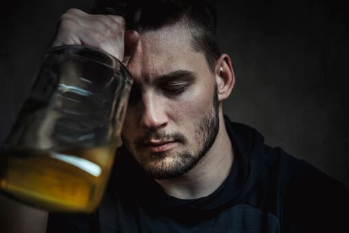 man holding a bottle is exhibiting the stages of alcoholism