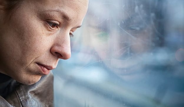 Woman looking out the window wondering what causes addiction