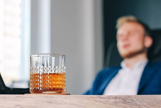 man sitting in front of a glass of alcohol during Alcohol Awareness Month
