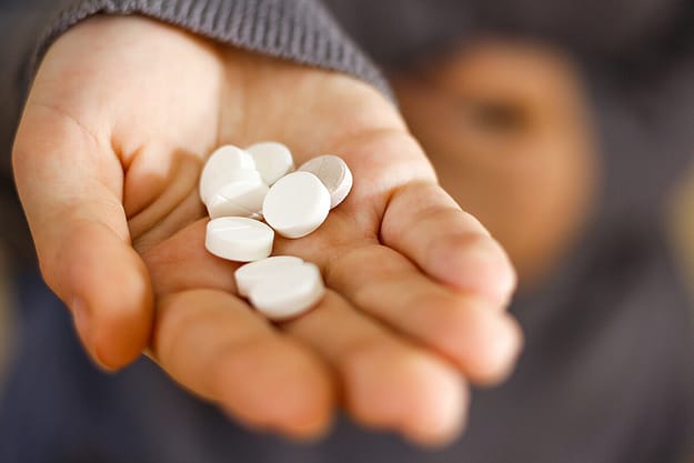 a person holds a pile of white pills and wonders what opioids are