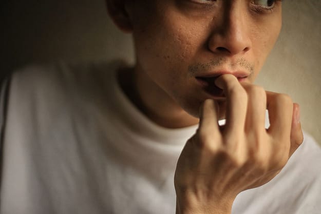 a man nibbles his nails and thinks about the clear signs of drug use