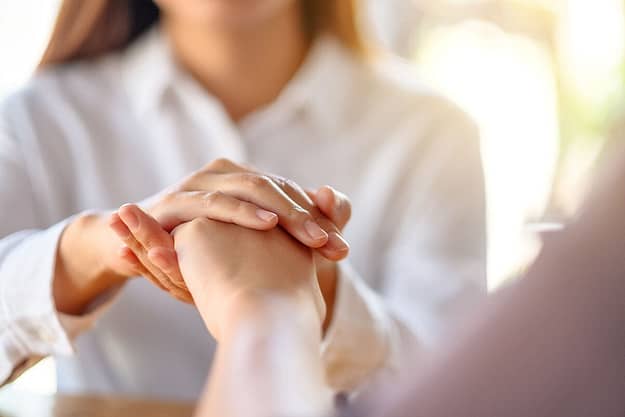 a therapist holds a client's hand as she tells him how to help an addict recover