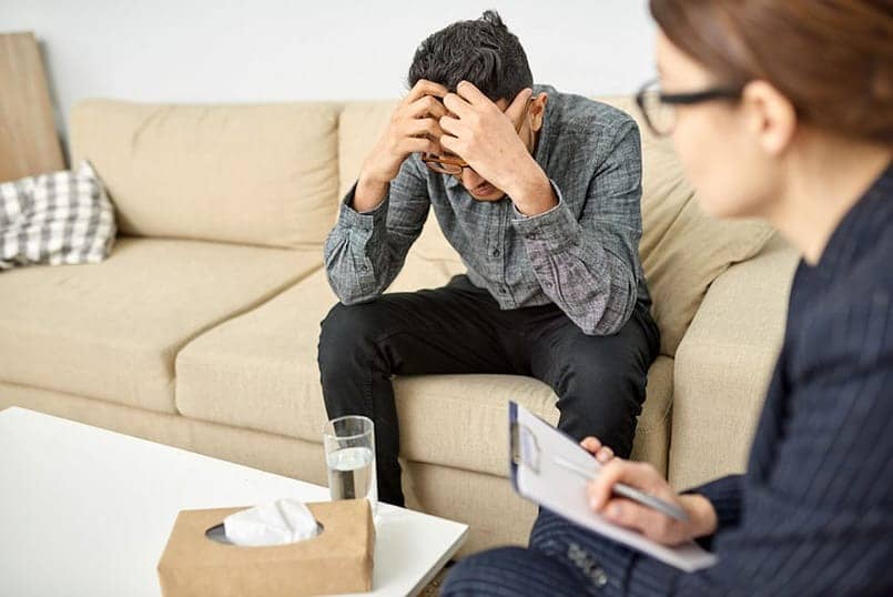 man with anxiety sitting on couch in therapy