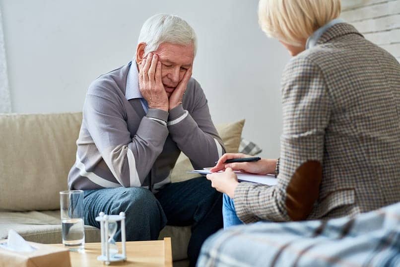 senior man sitting with his head in hands in individual therapy