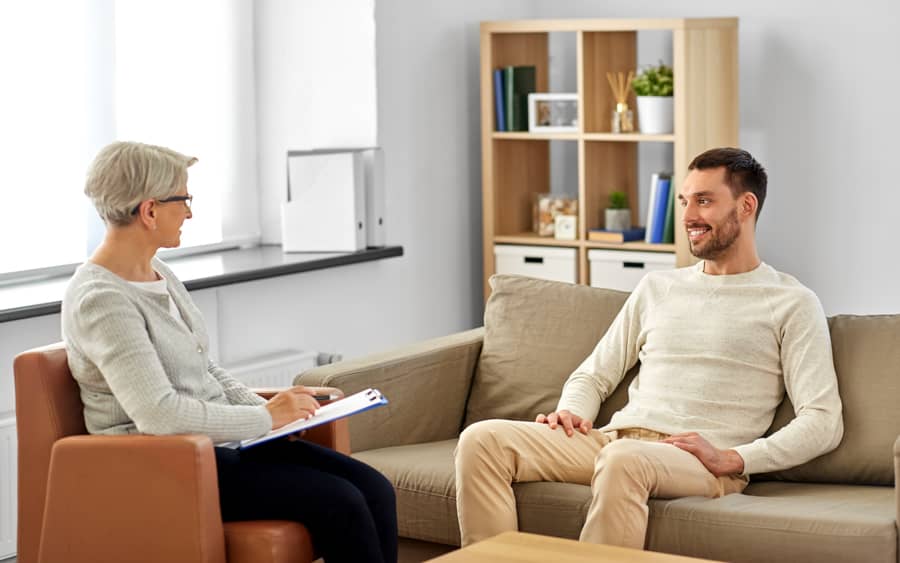 man sitting in therapy with female therapist