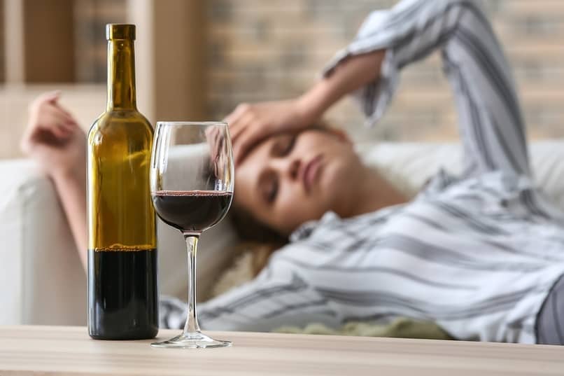 woman lying on couch looking at wine