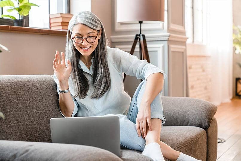 woman sitting on couch doing telehealth session at home