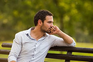 Worried man on park bench concerned about his relapse prevention plan.