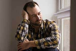 Worried looking man by window wants to remember how to prevent drug relapse