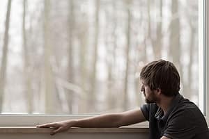 Man at rehab window suffering from anxiety and addiction
