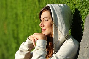 Woman in hoodie enjoying sun during a women's rehab program stay.