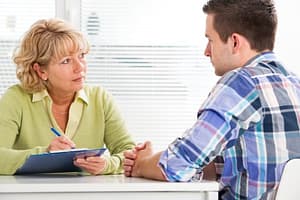 Female counselor explaining psychological addiction to drugs to male client.