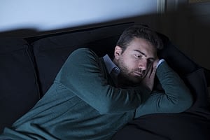 Depressed man in dark dealing with post-acute withdrawal syndrome.