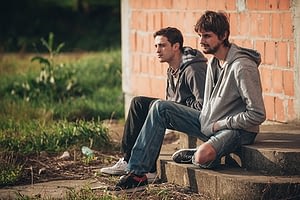 Two sad lonely homeless men showing signs of crack addiction