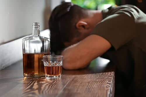 man with whiskey bottle wonders how to quit drinking