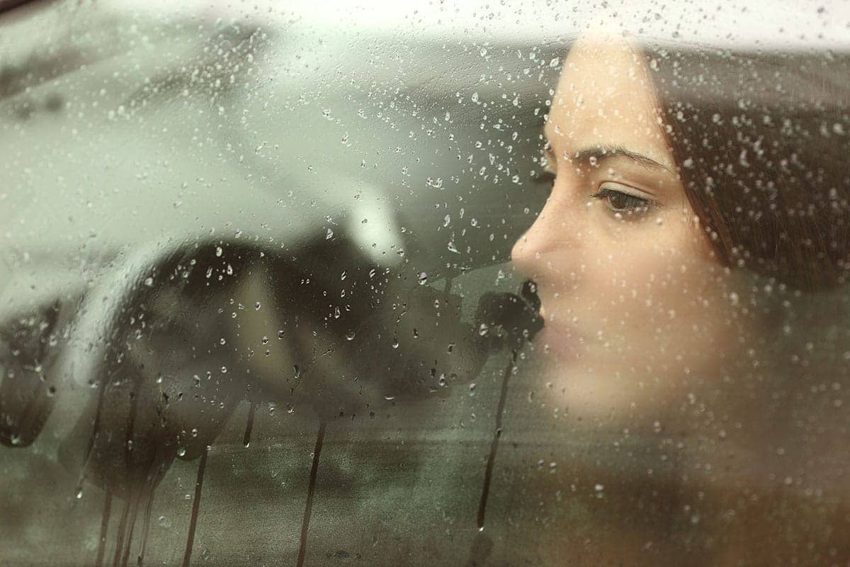 a woman looking out a car window thinking about the definition of addiction