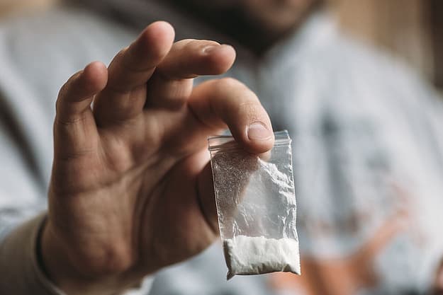 man sits and holds a bag of cocaine thinking about the effects of cocaine