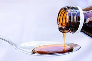 Cough syrup is poured into a spoon in an amount that would not be able to give you a dextromethorphan high